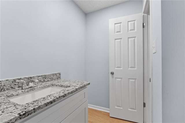 bathroom with baseboards, wood finished floors, and vanity