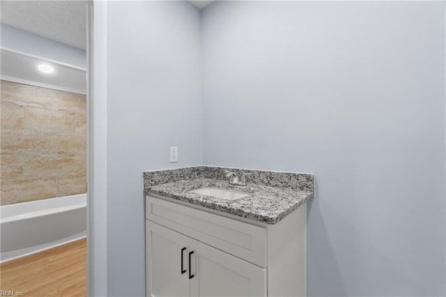 bathroom featuring wood finished floors, vanity, and a bathing tub