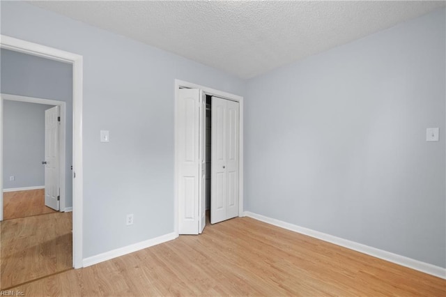 unfurnished bedroom with light wood-type flooring, a closet, and baseboards