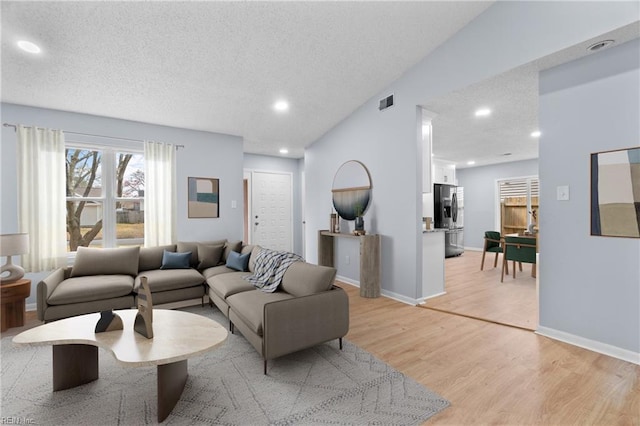 living area with light wood-style flooring, baseboards, a textured ceiling, and recessed lighting