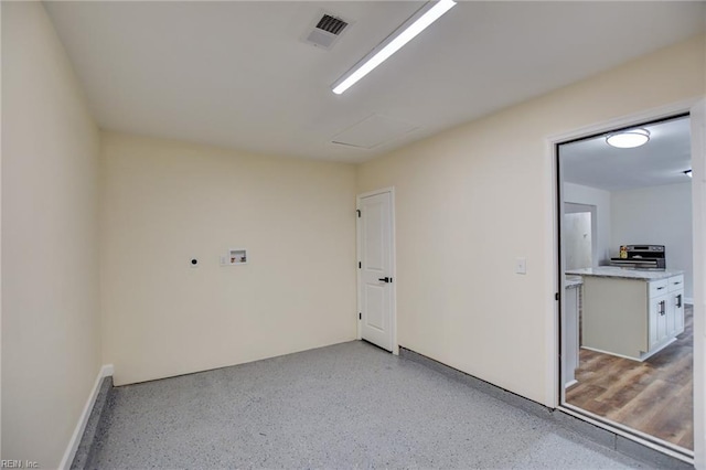 empty room featuring attic access, visible vents, and light speckled floor