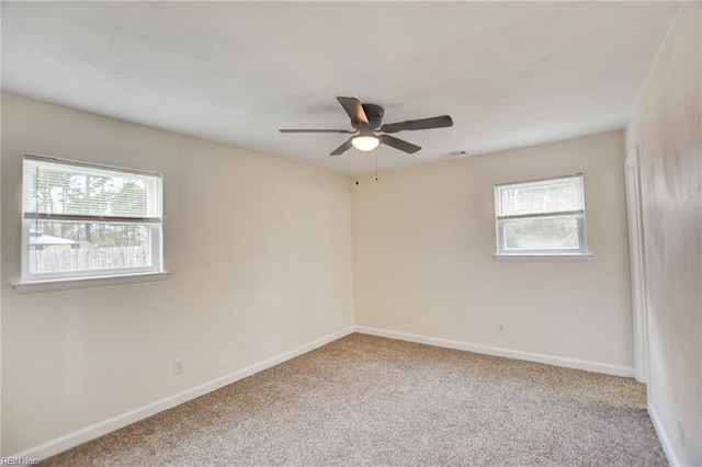 carpeted spare room featuring visible vents, plenty of natural light, baseboards, and ceiling fan