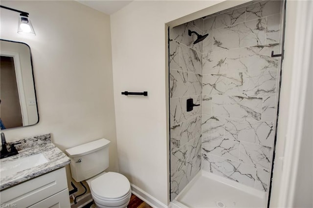 bathroom with toilet, a shower stall, vanity, and baseboards