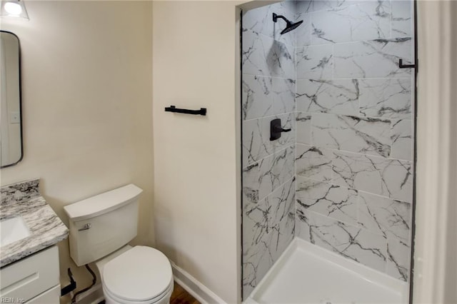 bathroom featuring toilet, a shower stall, baseboards, and vanity