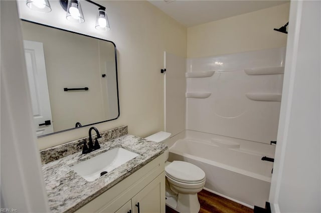 bathroom with toilet, washtub / shower combination, wood finished floors, and vanity