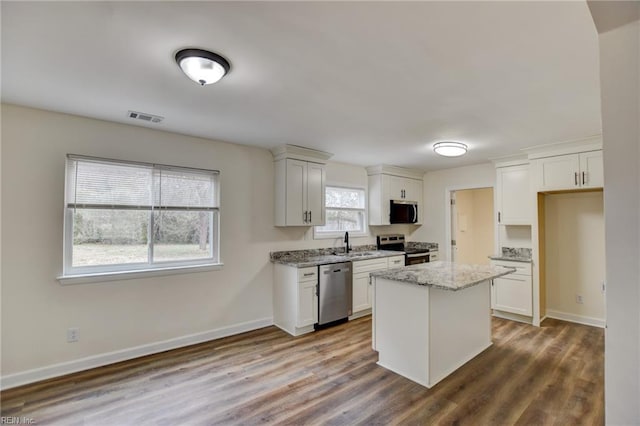 kitchen with stainless steel appliances, dark wood-style flooring, visible vents, baseboards, and light stone countertops