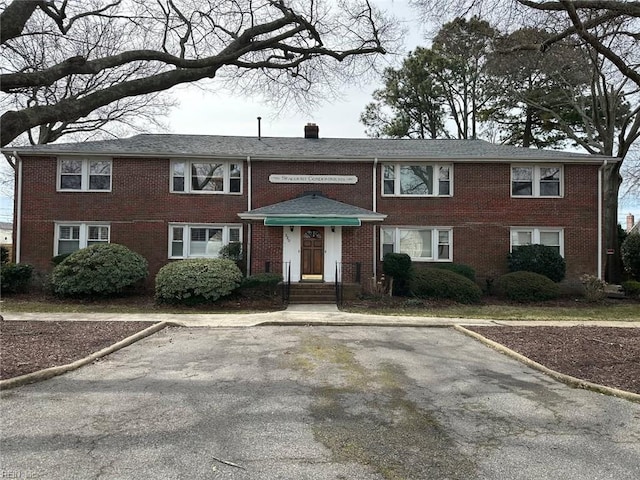 view of front of property featuring brick siding and a chimney