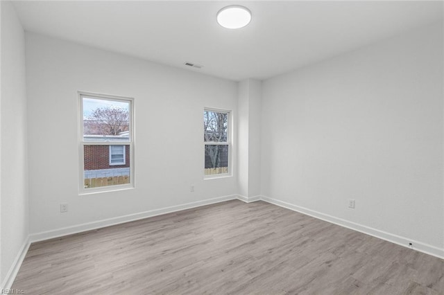 unfurnished room featuring baseboards, visible vents, and wood finished floors