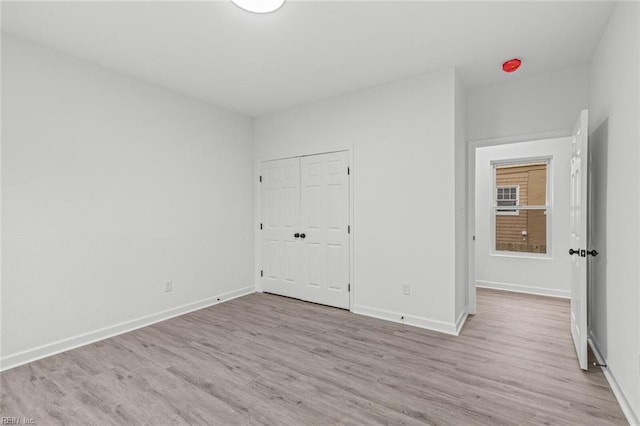 unfurnished bedroom with light wood-type flooring, baseboards, and a closet