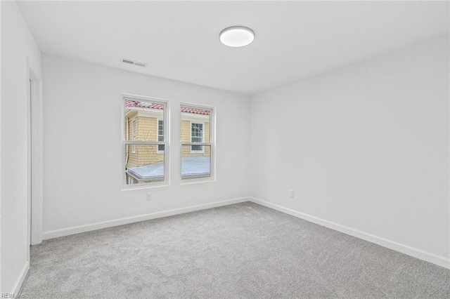 carpeted empty room featuring visible vents and baseboards