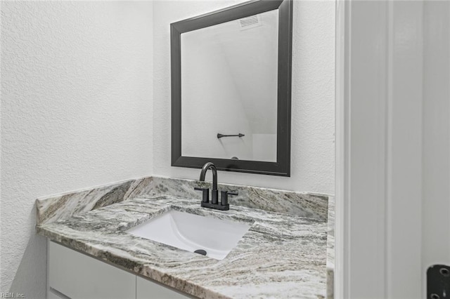 bathroom with a textured wall and vanity