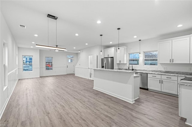 kitchen with visible vents, light wood-style flooring, appliances with stainless steel finishes, white cabinetry, and a kitchen island