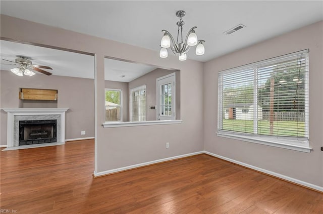unfurnished living room featuring a fireplace, wood finished floors, visible vents, and baseboards