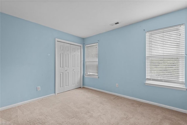 unfurnished bedroom with carpet floors, baseboards, and visible vents