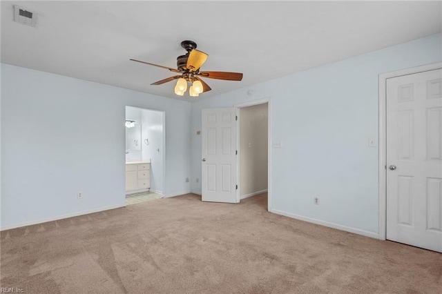 unfurnished bedroom featuring light carpet, ensuite bathroom, visible vents, and baseboards