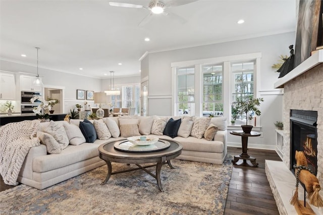 living area featuring dark wood-style floors, ornamental molding, a fireplace, and recessed lighting