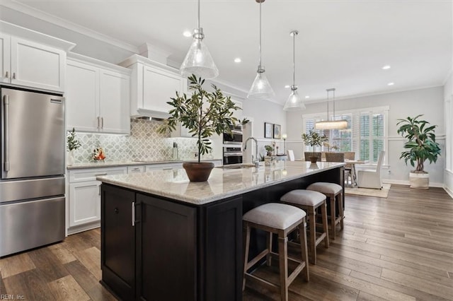 kitchen with white cabinets, decorative backsplash, ornamental molding, stainless steel appliances, and a sink