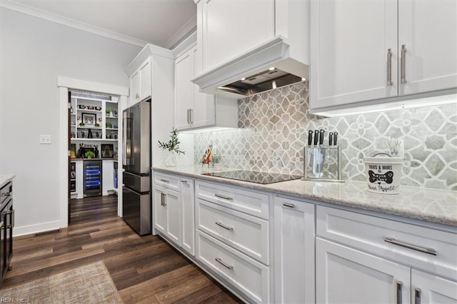 kitchen featuring wine cooler, black electric stovetop, high end fridge, custom range hood, and white cabinetry