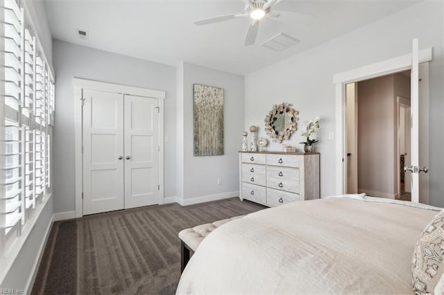 bedroom with a closet, visible vents, dark carpet, ceiling fan, and baseboards