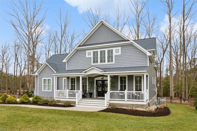 view of front facade with covered porch, roof with shingles, and a front lawn