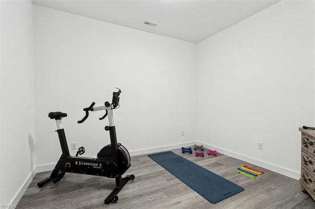 exercise room featuring wood finished floors, visible vents, and baseboards