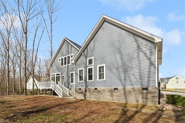 rear view of property featuring a deck, crawl space, fence, and stairway