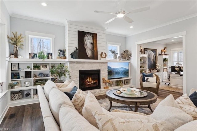 living area featuring a fireplace, wood finished floors, visible vents, and crown molding