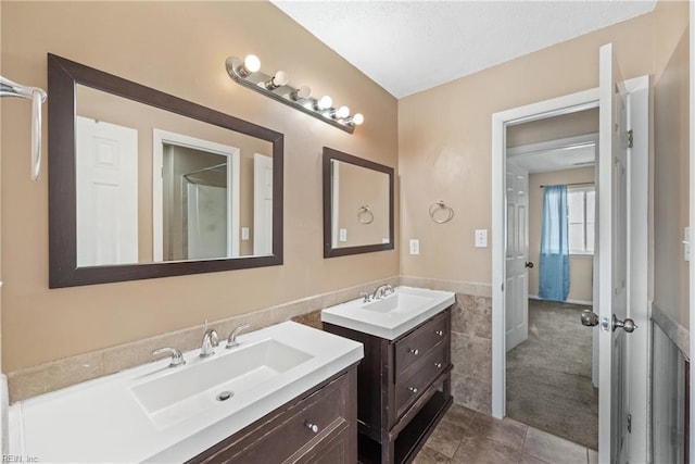 bathroom with a wainscoted wall, tile walls, two vanities, and a sink