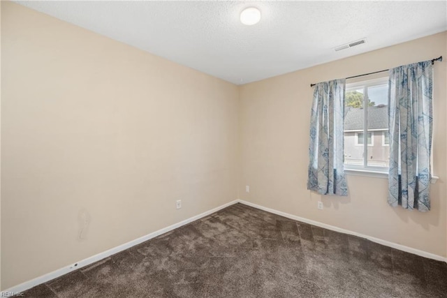 spare room featuring a textured ceiling, dark carpet, visible vents, and baseboards