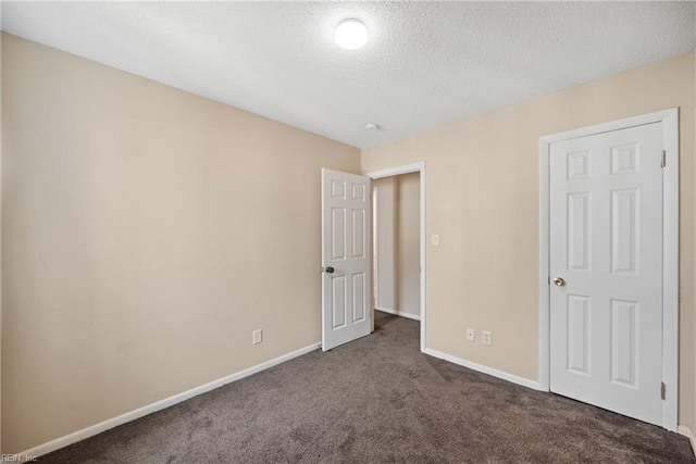 unfurnished bedroom featuring carpet flooring, a textured ceiling, and baseboards