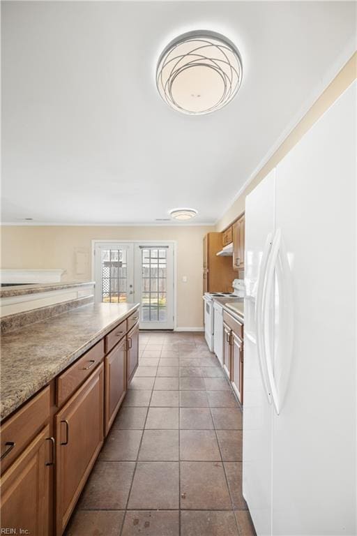 kitchen with brown cabinetry, white appliances, under cabinet range hood, and tile patterned floors