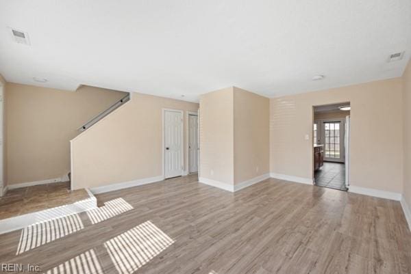 unfurnished living room featuring light wood-style floors, visible vents, and baseboards