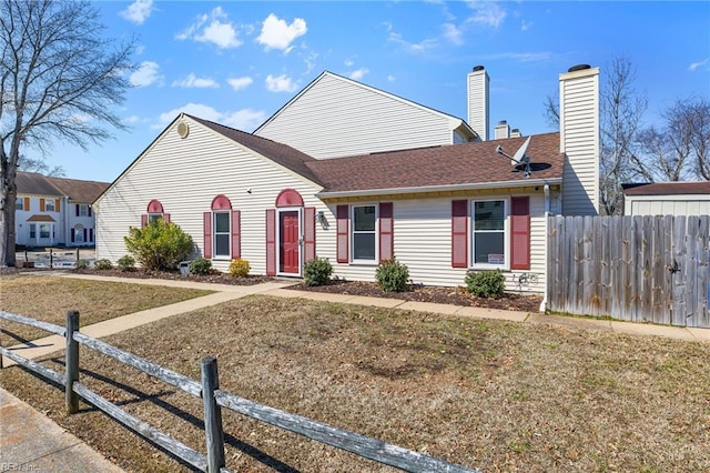 view of front of house with a front lawn, a chimney, and fence