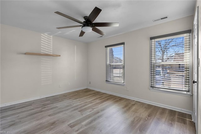 unfurnished room featuring a ceiling fan, visible vents, baseboards, and wood finished floors