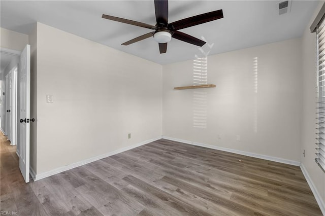 unfurnished room with wood finished floors, visible vents, and baseboards