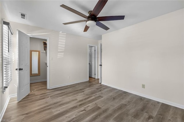 unfurnished bedroom featuring a ceiling fan, visible vents, baseboards, and wood finished floors