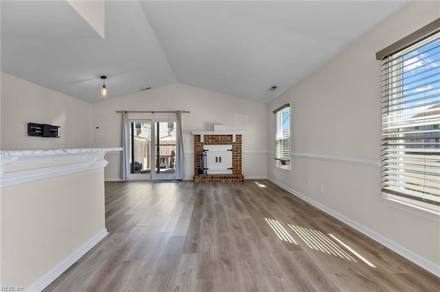 unfurnished living room with lofted ceiling, a fireplace, wood finished floors, and baseboards