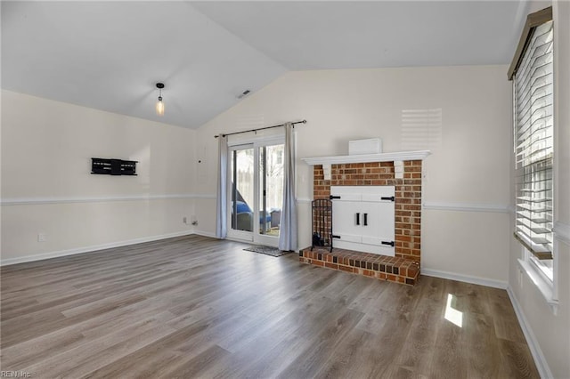 unfurnished living room featuring lofted ceiling, a fireplace, wood finished floors, and visible vents