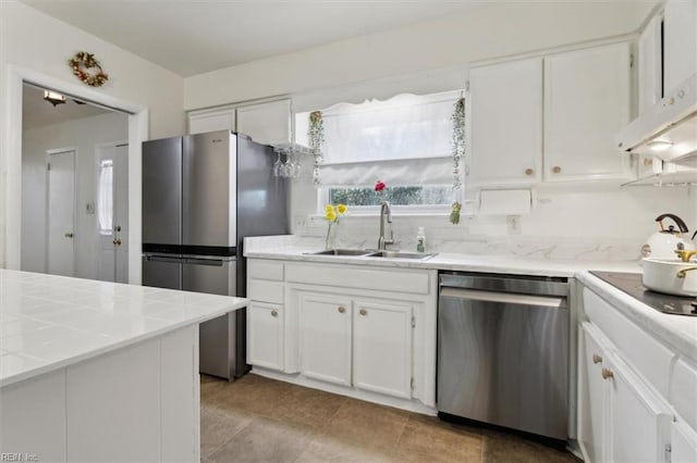 kitchen with a sink, appliances with stainless steel finishes, light countertops, and white cabinetry