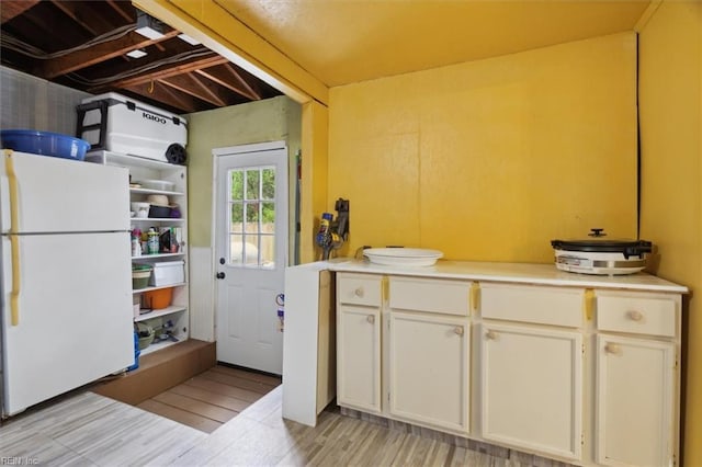 kitchen featuring light wood-type flooring, white cabinets, light countertops, and freestanding refrigerator