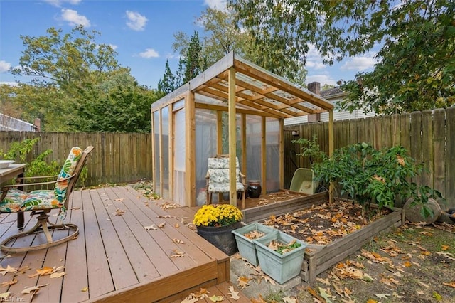 wooden terrace with an outbuilding, a garden, a greenhouse, and a fenced backyard