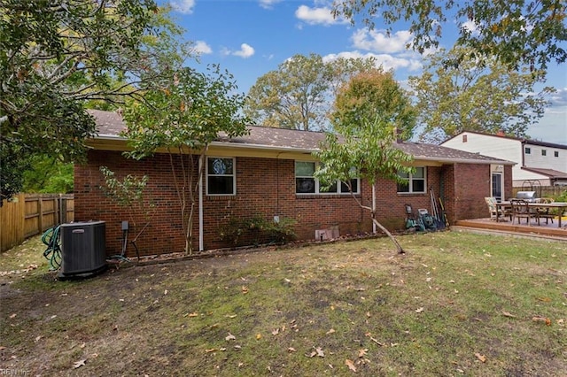 back of house with fence, brick siding, central AC, and a lawn