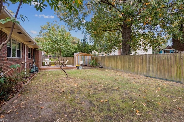 view of yard featuring a storage shed, an outbuilding, a fenced backyard, and a patio area