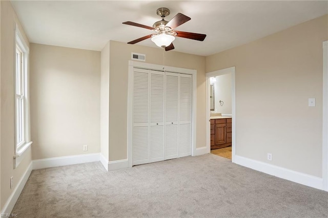 unfurnished bedroom with light carpet, baseboards, visible vents, multiple windows, and a closet