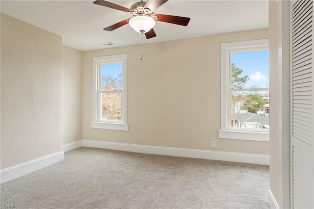 carpeted spare room with a wealth of natural light, ceiling fan, and baseboards