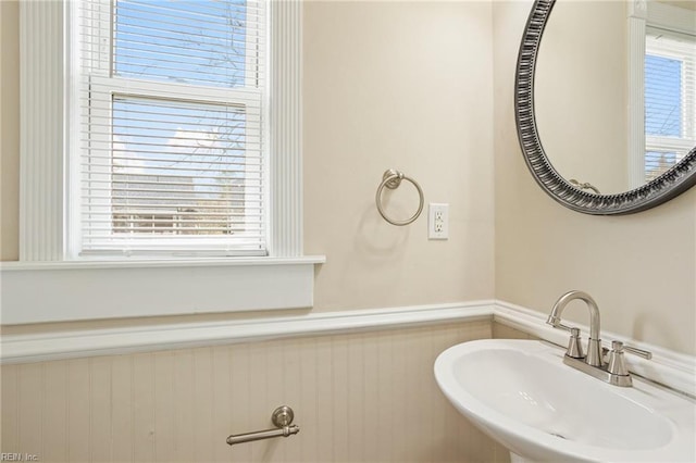 bathroom with plenty of natural light, a wainscoted wall, and a sink