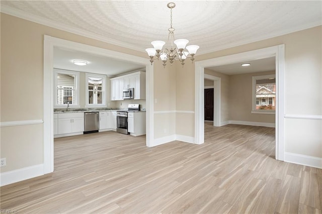 interior space featuring appliances with stainless steel finishes, light wood-type flooring, white cabinets, and baseboards