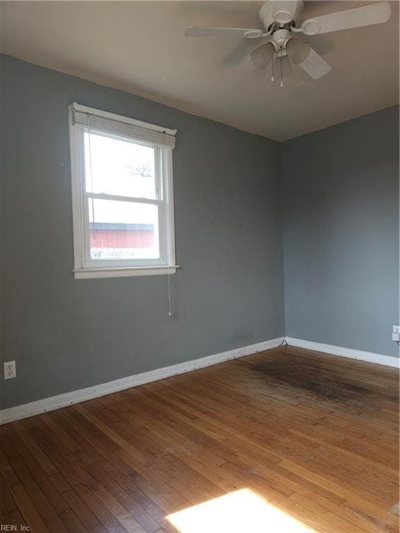 spare room with a ceiling fan, hardwood / wood-style floors, and baseboards