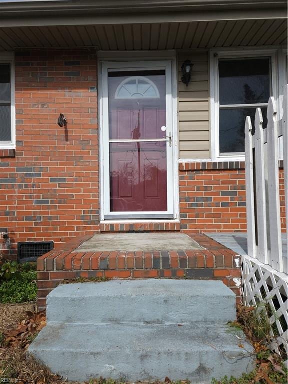 entrance to property featuring crawl space and brick siding