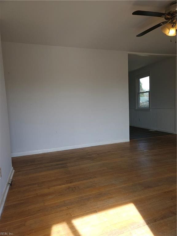 empty room with dark wood-style floors, ceiling fan, and baseboards